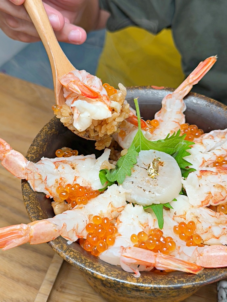 筷子夾起炙燒鮮蝦、干貝與鮭魚卵