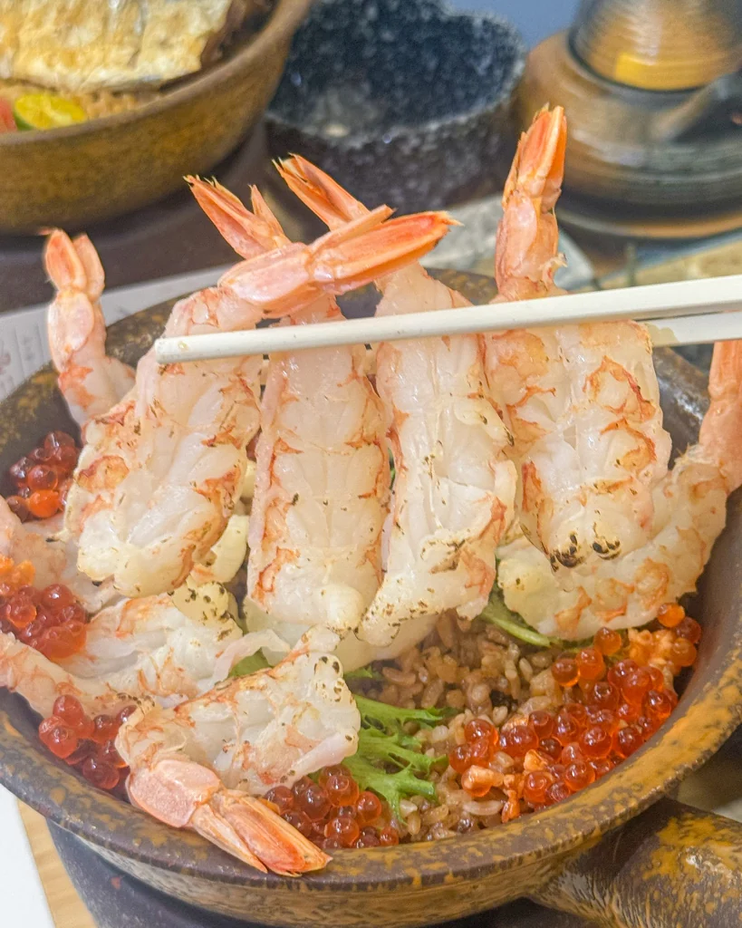 筷子夾起炙燒干貝蝦雙拼釜飯的蝦肉