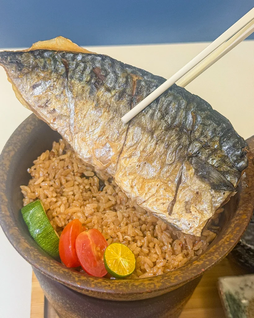 筷子夾起鹽烤鯖魚釜飯的鯖魚