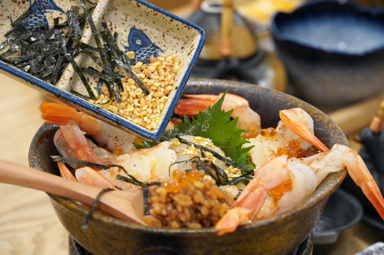 筷子將海苔與芝麻配料加入炙燒干貝鮮蝦釜飯