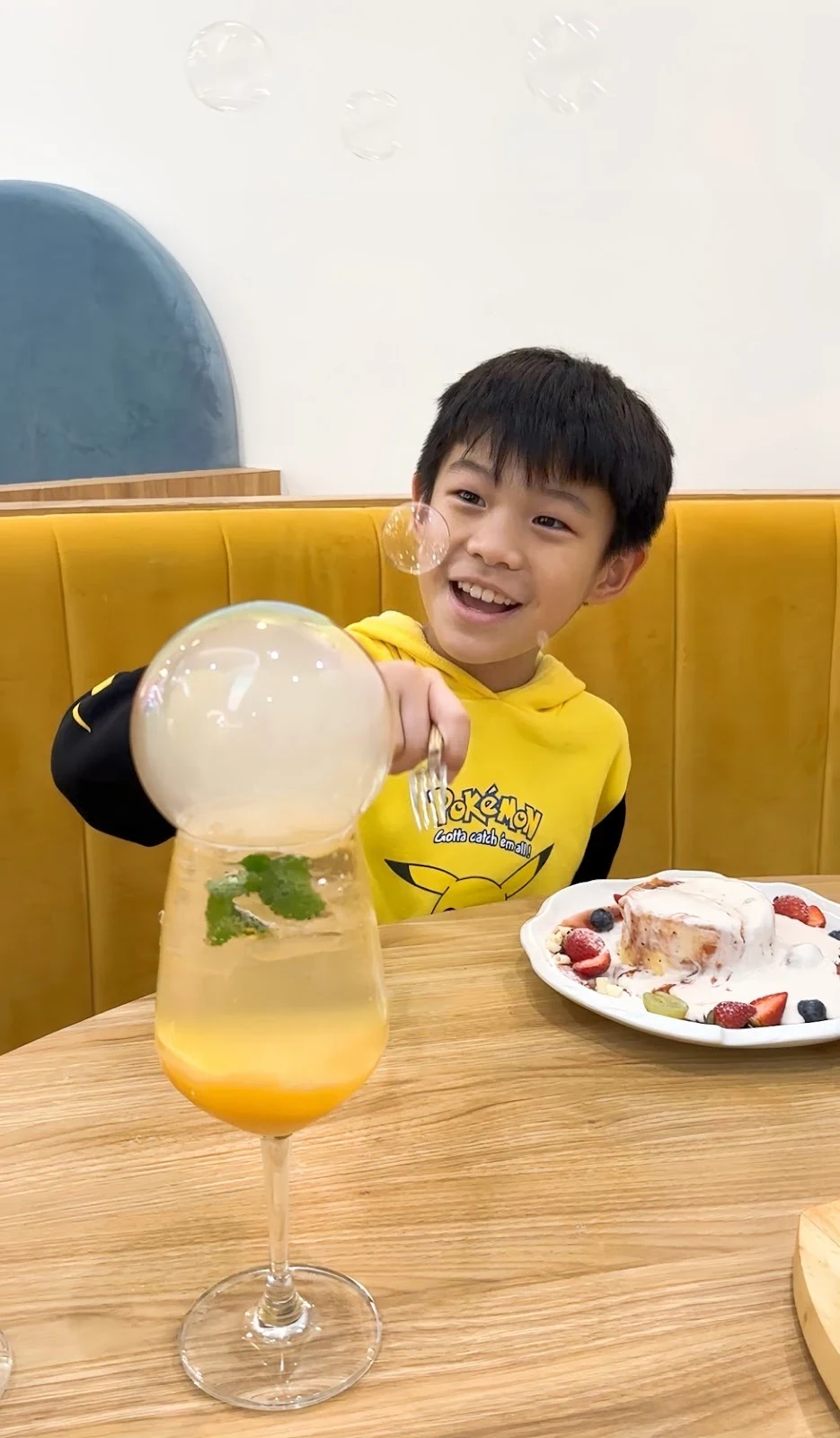 孩童坐在氣泡飲旁觀察泡泡