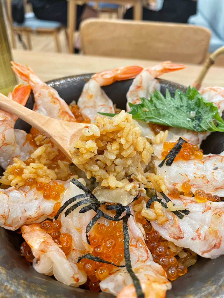 湯匙舀起鮮蝦鮭魚卵與雞高湯釜飯